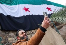 شاب يلتقط صورة سيلفي مع العلم الوطني لسورية في منطقة باب توما